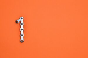 Metal chain forming the number one on an orange background, ideal for design concepts.