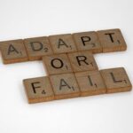 Scrabble tiles spell 'Adapt or Fail' on a white background, conveying a motivational message.