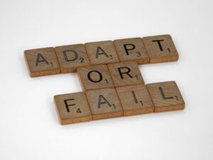 Scrabble tiles spell 'Adapt or Fail' on a white background, conveying a motivational message.